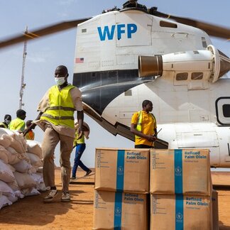 بالگرد شنوک برنامه جهانی غذا (WFP) در شهر جیبو، بورکینافاسو توسط باربران تخلیه می‌شود.