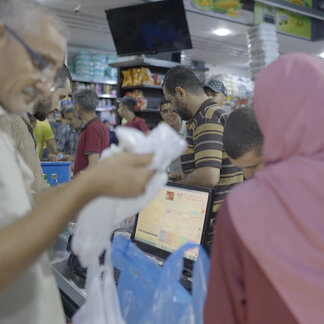 مردی در حال ریختن غذا در کیسه برای زنی در مغازه