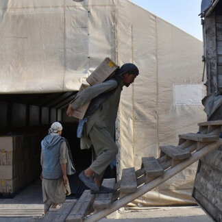 کارمندان برنامه جهانی غذا، جعبه‌هایی حاوی کمک‌های غذایی غنی شده را برای توزیع در افغانستان حمل می‌کنند.