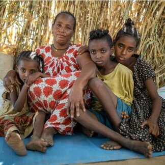زنی همراه با فرزندانش که به‌دلیل درگیری‌ها در سودان آواره شده‌اند.